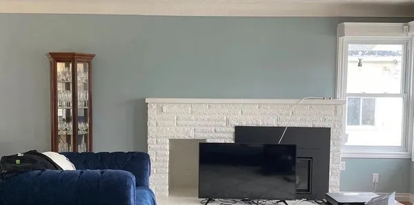 Living room after: soft blue walls and a white fireplace