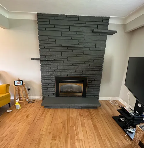 Stone fireplace surround painted deep charcoal, with matching hearth and shelves