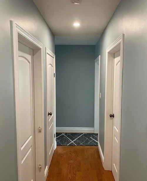Blue-grey hallway with white doors and trim