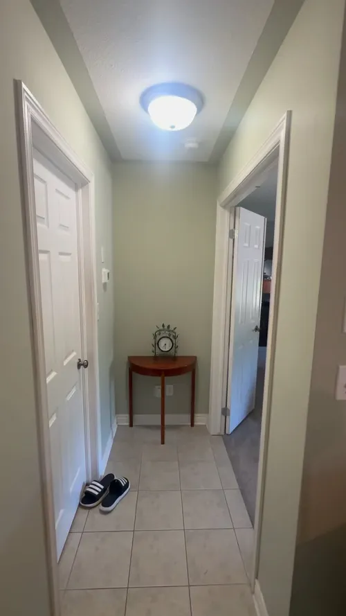 Narrow hallway in soft sage with white doors and trim