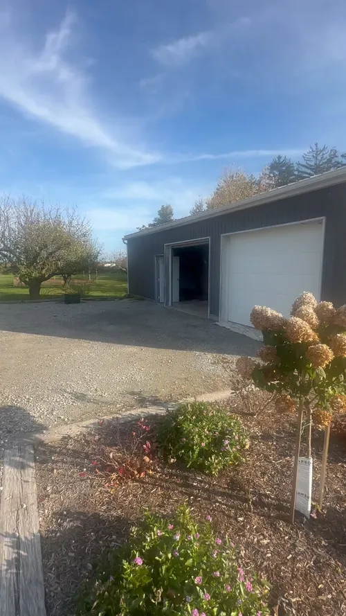 Large outbuilding with dark grey siding and white doors and trim