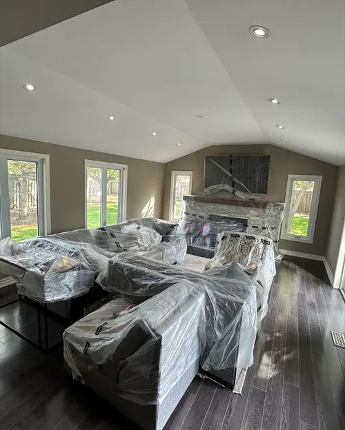 Living room furniture and TV wrapped in plastic before painting