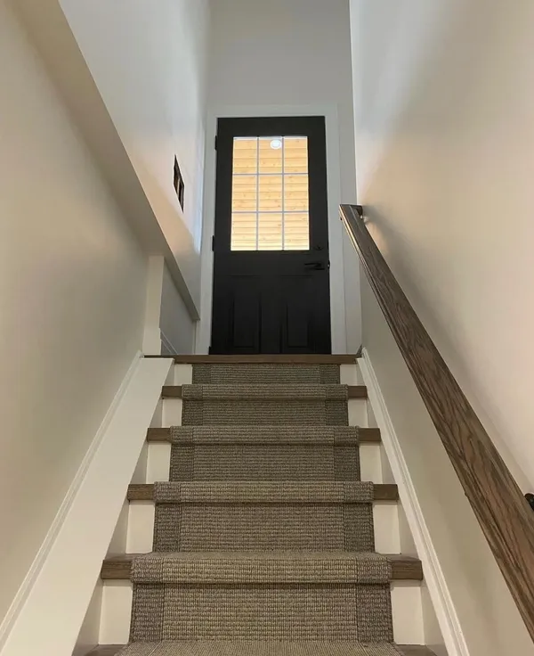 Stairwell painted white with a black door at the top