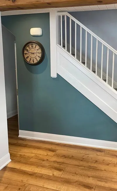 Teal feature wall under a white staircase